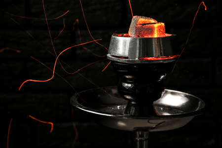 Burning coal for hookah on dark background