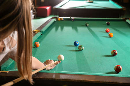 Young woman playing billiard in club