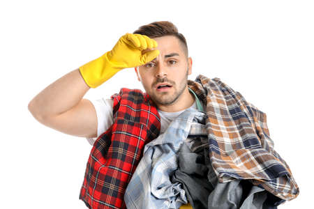 Tired young man with laundry on white backgroundの写真素材