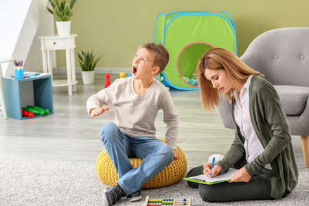 Female psychologist working with boy suffering from autistic disorder
