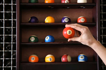 Woman taking billiard ball from shelfの写真素材
