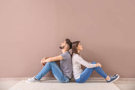 Young couple sitting near color wallの写真素材