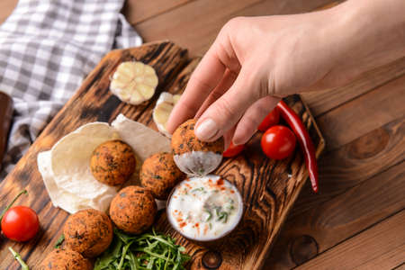Woman eating tasty falafel balls with sauce, closeupの写真素材