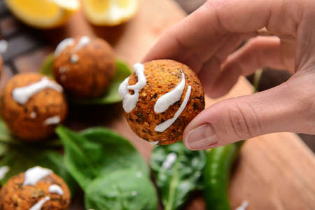 Woman eating tasty falafel balls with sauce, closeup