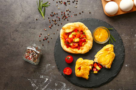 Slate plate with delicious vegetable samosas and sauce on tableの写真素材