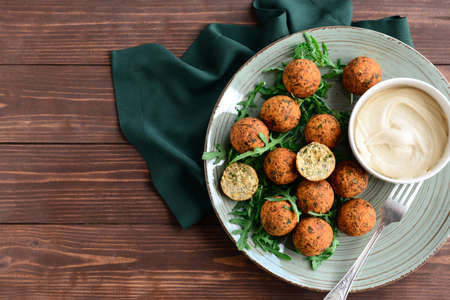 Plate with tasty falafel balls and sauce on wooden tableの写真素材
