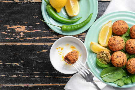 Tasty falafel balls with sauce on wooden table
