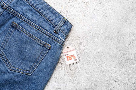 Stylish jeans with tag on light backgroundの写真素材