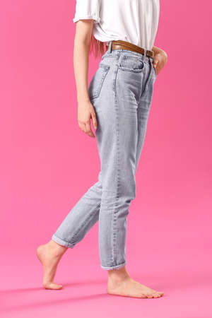 Stylish young woman in jeans on color backgroundの写真素材