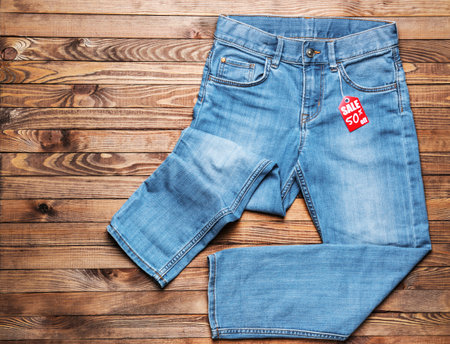 Stylish jeans with tag on wooden backgroundの写真素材