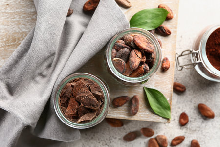 Jars with cocoa beans and chocolate on light backgroundの写真素材