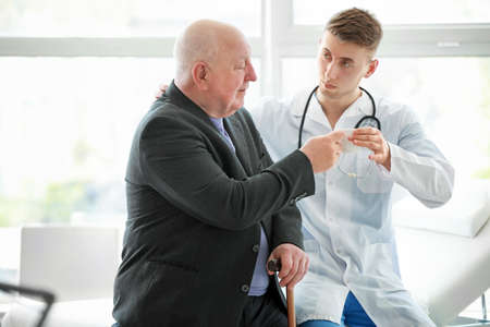 Doctor examining senior man in nursing homeの写真素材
