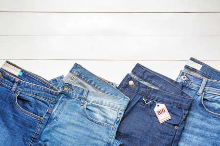 Stylish jeans with tag on wooden background