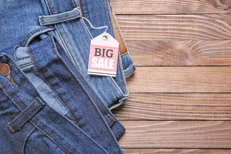 Stylish jeans with tag "BIG SALE" on wooden background, closeupの写真素材