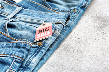 Stylish jeans with tag "Big Sale" on light background, closeupの写真素材