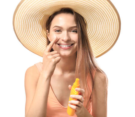 Beautiful young woman applying sun protection cream against white background