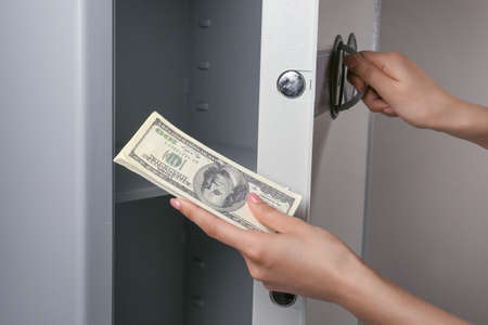 Woman with money opening modern safe, closeupの写真素材