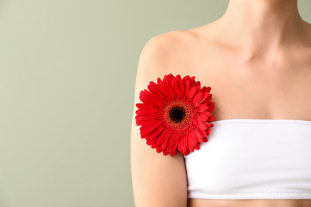 Beautiful young woman with flower on color background. Depilation conceptの写真素材