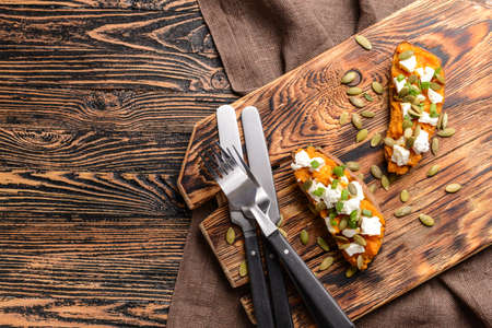 Baked sweet potato with cheese and arugula on wooden backgroundの写真素材