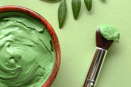 Cosmetic clay in bowl with brush on color background