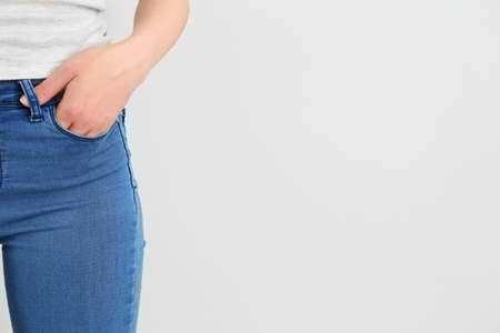 Young woman wearing stylish jeans pants on light backgroundの写真素材