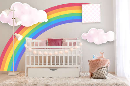 Interior of light modern baby room with crib and painting of rainbow on wallの写真素材