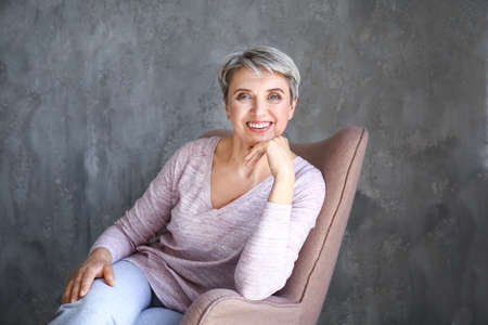 Portrait of beautiful mature woman on gray backgroundの写真素材