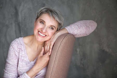 Portrait of beautiful mature woman on gray backgroundの写真素材