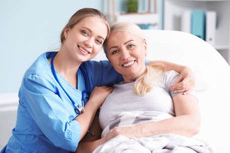 Medical assistant with mature patient in clinicの写真素材