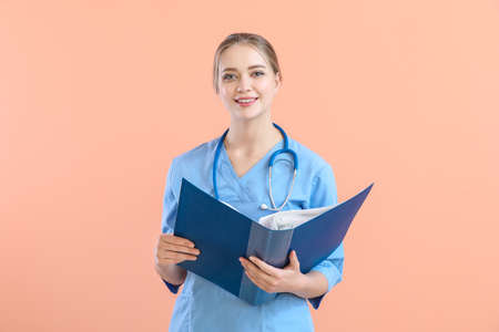 Young medical assistant with documents on color background