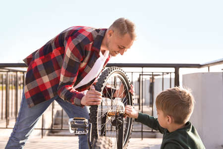 Father and his son repairing bicycle outdoorsの写真素材