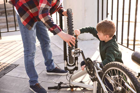 Father and his son repairing bicycle outdoorsの写真素材
