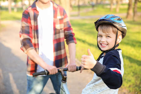Father teaching his son to ride bicycle outdoorsの写真素材
