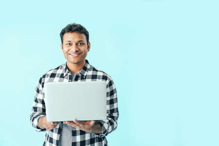 Happy man with laptop on color backgroundの写真素材
