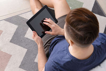 Handsome man with tablet computer resting in bedroom