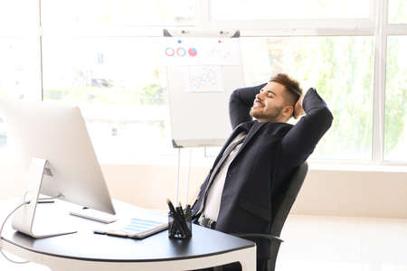 Handsome businessman having break during work in officeの写真素材