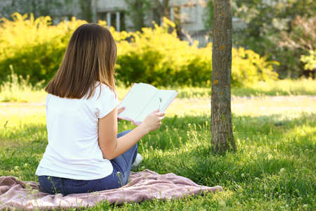 Beautiful young woman reading book in parkの写真素材