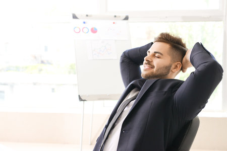 Handsome businessman having break during work in officeの写真素材