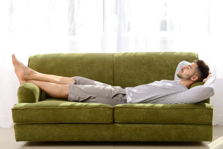 Handsome man sleeping on sofa at homeの写真素材