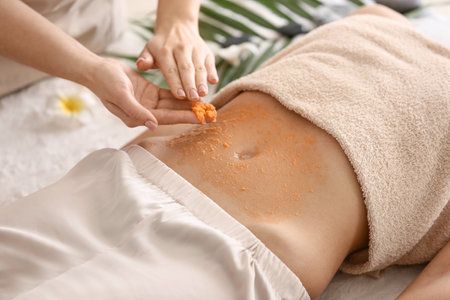 Young woman undergoing treatment with body scrub in spa salonの写真素材