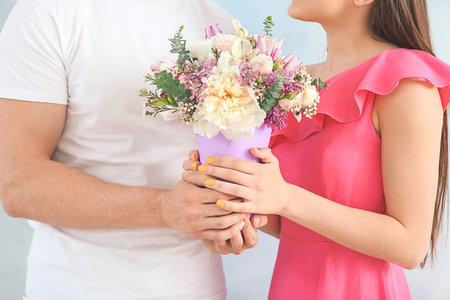 Young couple with bouquet of beautiful flowers on light background, closeupの写真素材