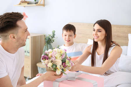 Family greeting young woman in bedroom at homeの写真素材