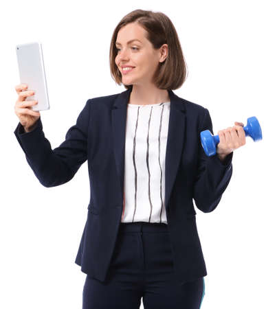 Young businesswoman with tablet PC and dumbbell on white background. Concept of balance between work and leisureの写真素材