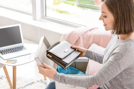 Young woman opening parcel with new purchase at home