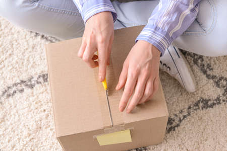 Young woman opening parcel at home, closeup