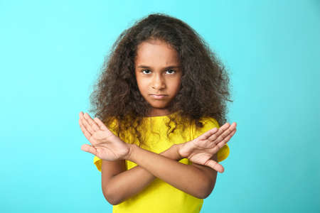 Cute African-American girl rejecting something on color backgroundの写真素材