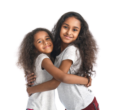Cute hugging African-American girls on white background