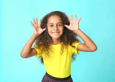 Cute African-American girl on color background