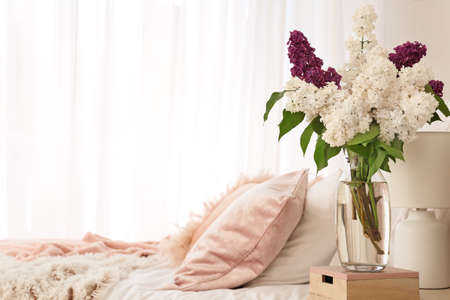Vase with beautiful lilac flowers in bedroomの写真素材