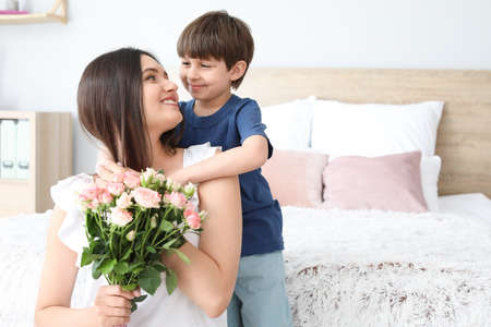 Happy mother and son with bouquet of flowers at homeの写真素材